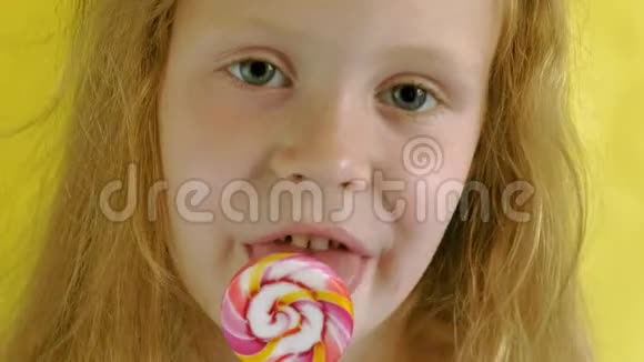 黄色背景上有棒棒糖的小女孩特写肖像视频的预览图