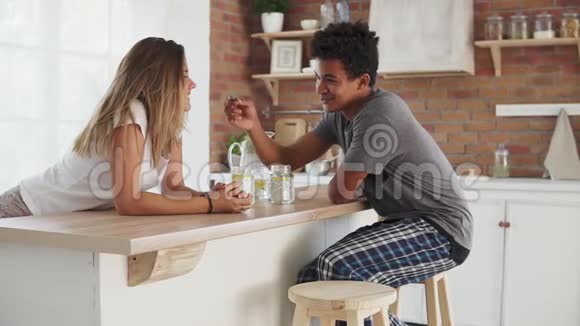 年轻的多民族夫妇早上在厨房的桌子旁交谈帅哥玩绿叶游戏视频的预览图
