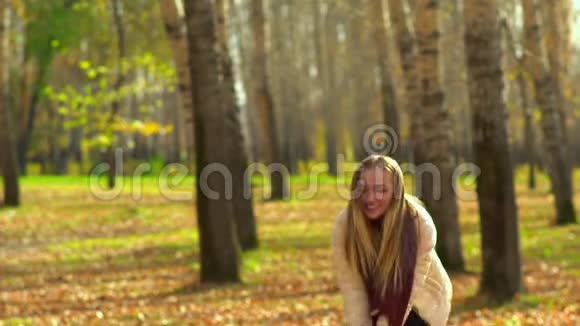 秋天公园里一个漂亮的女孩用手收集树叶然后扔出去视频的预览图