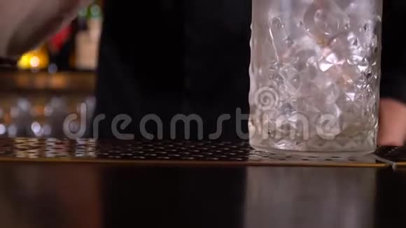 酒吧老板把饮料倒入盛满冰块的杯子里用长勺搅拌视频的预览图