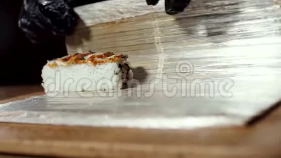 近距离观看厨师在黑色烹饪手套滚动寿司与makisu日本食品准备框架关闭视频的预览图