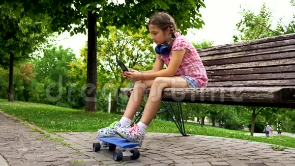 在公园的长椅上玩手机的漂亮女孩视频的预览图