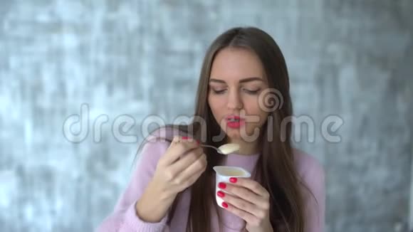 美丽的年轻女人的肖像长发吃酸奶女人吃酸奶的肖像健康妇女视频的预览图