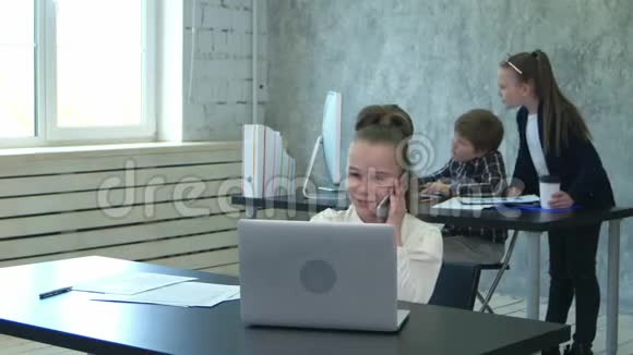 七岁的商业女孩在办公室内部工作在电脑上工作在电话上说话视频的预览图