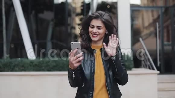 幸福的年轻女性在视频上讲话的肖像手机上的电话站在街道上的大楼附近视频的预览图