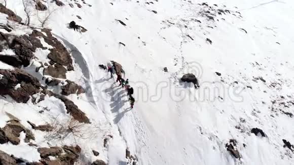 一群登山者排成一队试图克服通往雪坡顶部的道路视频的预览图