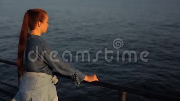年轻美丽的白人中年妇女红色头发穿着蓝色牛仔裙站在海边视频的预览图