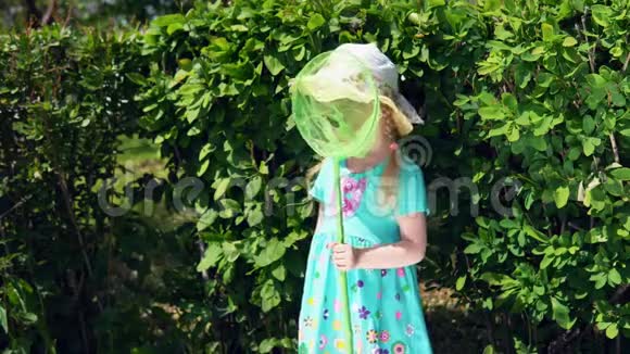 夏天小女孩在绿色灌木丛的背景上拿着铲子视频的预览图