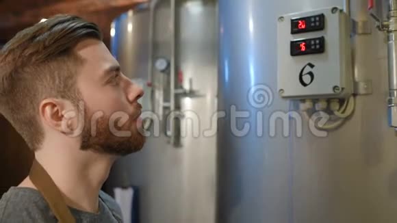 一个长胡子的啤酒人在啤酒罐和一家啤酒厂的背景下在平板电脑上做笔记视频的预览图