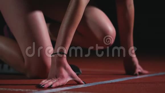 瘦小的女运动员站在适当的位置开始在跑道上的垫子上慢动作视频的预览图