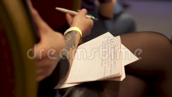 为了坐在椅子上的女人膝盖上放着一本复印本手里拿着一支钢笔艺术有纹身的年轻女孩视频的预览图
