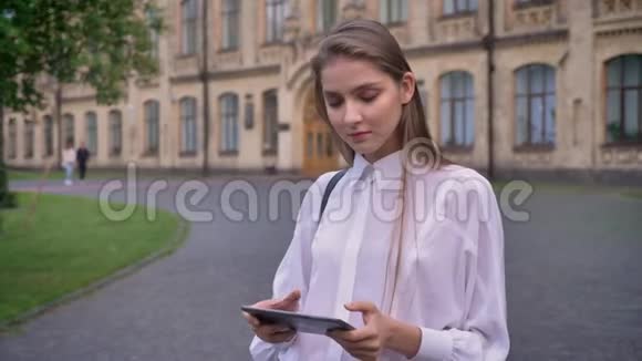 年轻漂亮的女学生在夏天的平板电脑上工作微笑着看着摄像机交流理念视频的预览图