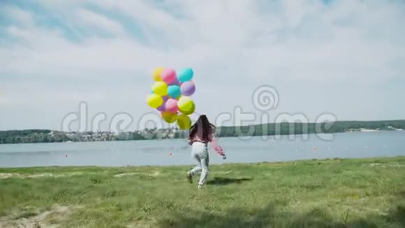 快乐的女孩带着五颜六色的气球跑到湖边4K视频的预览图