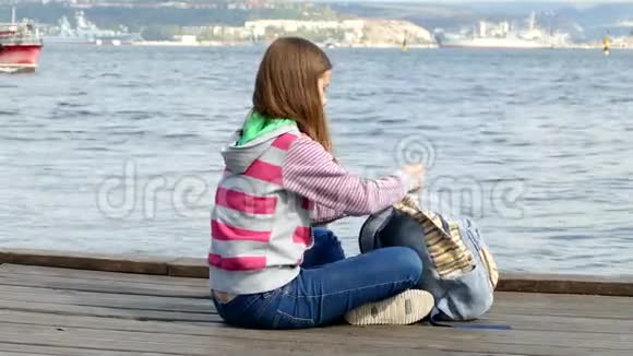 女孩正在海边的堤岸上读一本书视频的预览图