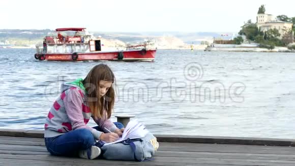 这个女孩正在海边的码头上做作业视频的预览图