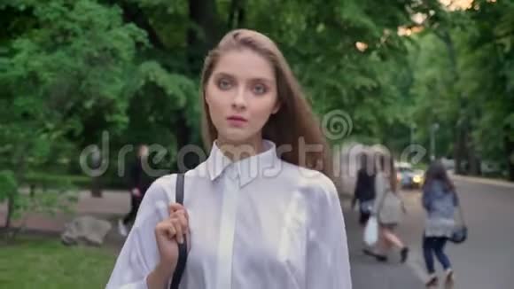 一个年轻漂亮的严肃女孩在夏天白天穿过公园想着自己的想法视频的预览图