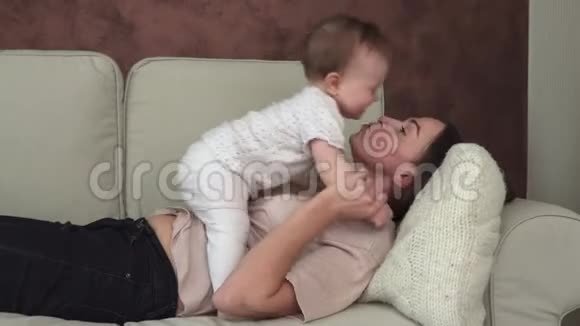 快乐的妈妈手牵着小宝宝在沙发上接吻视频的预览图