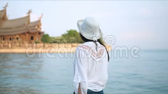 旅游女孩穿过海滨来到古庙视频的预览图