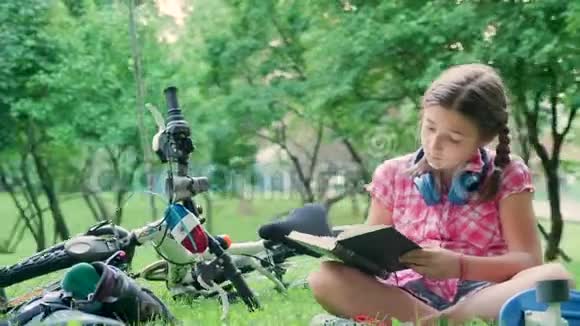 年轻活泼的女孩坐在公园的草地上看书视频的预览图