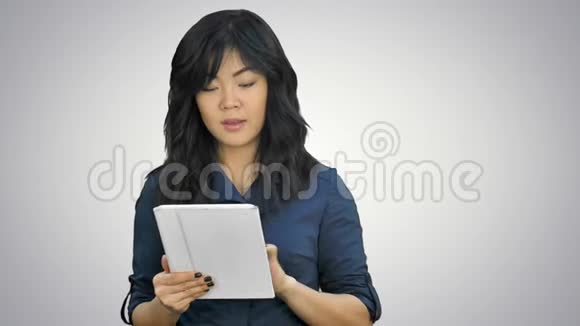 年轻的商务女性拥有平板电脑在白色背景下观看相机视频的预览图