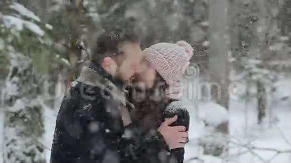 年轻漂亮的白种人夫妇在冬天的森林里在雪地里接吻时尚的千禧一代享受乐趣视频的预览图
