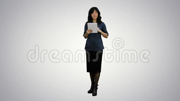 亚洲女人看着镜头说话拿着白色背景的数码平板电脑视频的预览图