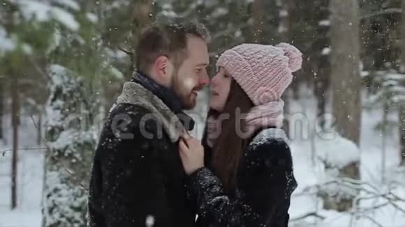 年轻漂亮的白种人夫妇在冬天的森林里在雪地里接吻时尚的千禧一代享受乐趣视频的预览图