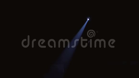 在一场演出中在剧院或马戏团的黑暗中来自单一聚光灯的蓝光闪电设备视频的预览图