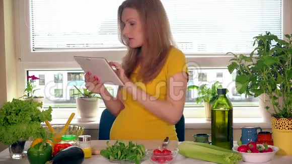 准妈妈用平板电脑找蔬菜沙拉原料视频的预览图