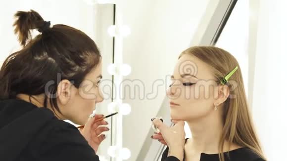 女人在婚礼前为年轻女人化妆眉毛和脸女人脸上画着眉毛视频的预览图