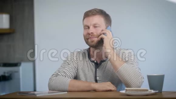 一个男人坐在厨房里在打电话早餐咖啡和愉快的谈话时间视频的预览图