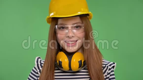 年轻的微笑红发女孩戴着建筑头盔耳机护目镜像标志视频的预览图