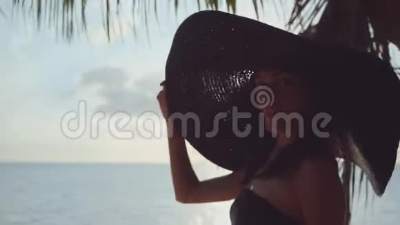 摄影师在海滩上用黑色太阳帽瞄准剪影模型视频的预览图
