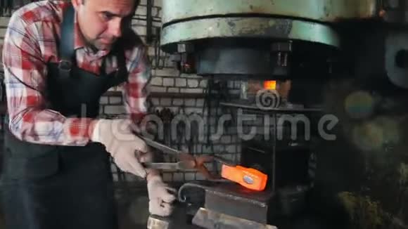 铁匠在工作时用电锤靠近铁砧红色的热钢锻造视频的预览图