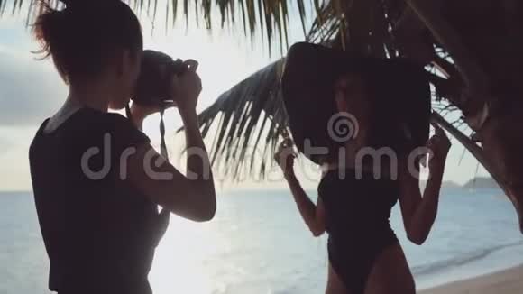 摄影师在海滩上用黑色太阳帽瞄准剪影模型视频的预览图