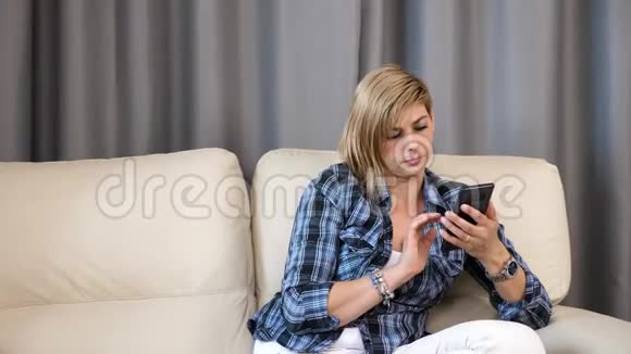 客厅沙发上的女人正在检查她的手机当她十几岁的女儿跳进她的怀里视频的预览图