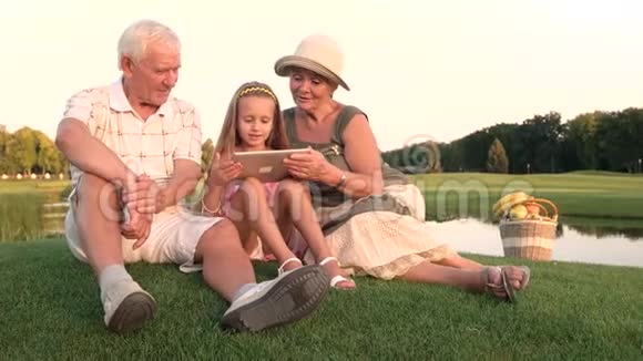 老年人和孙女使用个人电脑平板电脑户外视频的预览图
