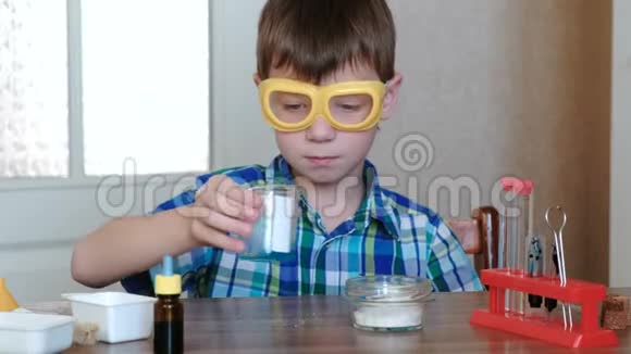 家庭化学实验特写男孩他的手混合了物质和烧杯中的蓝色液体视频的预览图