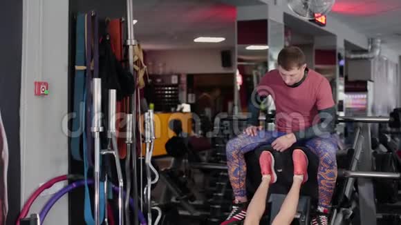 非常漂亮和健身模型训练腿在模拟器上与一个人在健身房视频的预览图