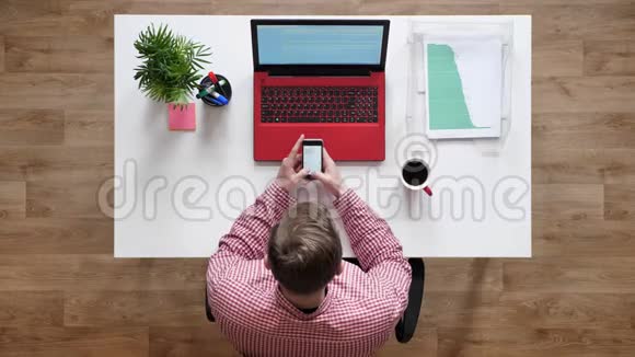年轻人打电话发短信顶头坐在桌子后面拿着笔记本电脑和咖啡视频的预览图