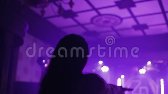 有长发的女人在俱乐部跳舞前面是蓝色的聚光灯慢动作视频的预览图