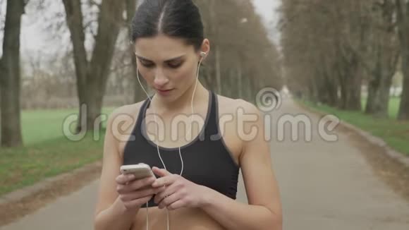 年轻的fsport女孩在智能手机上播放音乐跑步健康的生活方式运动观念视频的预览图
