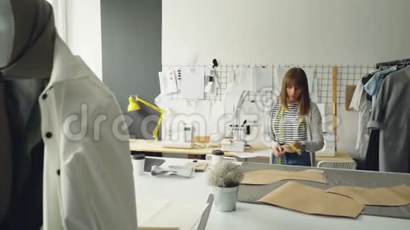 年轻迷人的女设计师正在用测量带检查她的纸模板专业创意服装视频的预览图