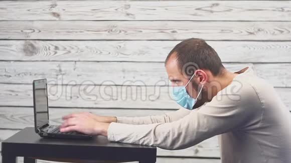 生病的商人使用笔记本电脑在办公室工作时有温度和头痛戴着口罩的男人视频的预览图