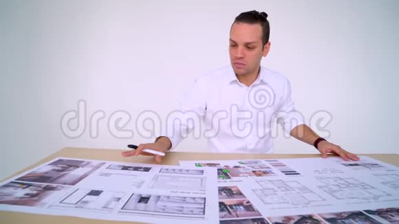 年轻设计师的肖像他在办公桌上用绘图尺子和铅笔工作穿毛衣的男人拿着办公室用品视频的预览图