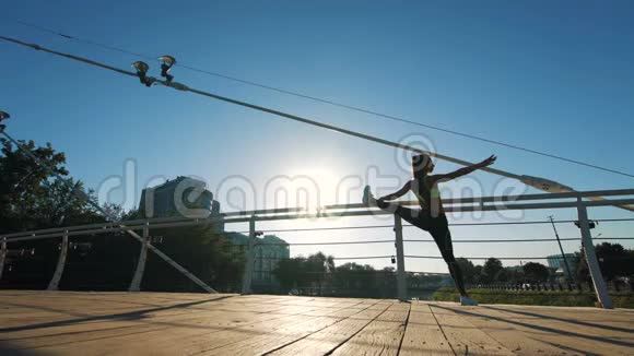 在人行天桥上的城市公园里电影院里活跃的女性剪影在锻炼和伸展视频的预览图