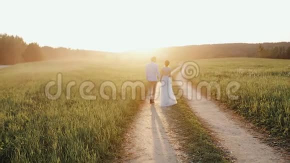 一对夫妻一男一女在夕阳下牵着手走在乡间的路上视频的预览图