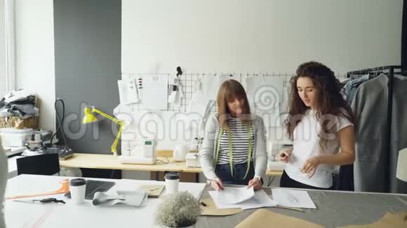 年轻的时装设计企业家正在他们的灯光工作室里讨论新衣服收藏的草图妇女视频的预览图