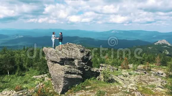 山上的几名游客举起双手享受自由快乐的男人和女人看着风景天际线视频的预览图