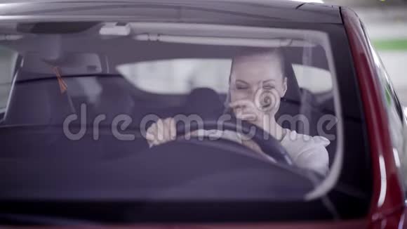 马尾辫的女人坐在红色的车里在方向盘后面微笑视频的预览图
